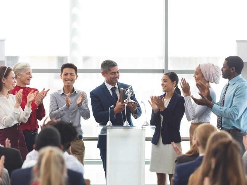 businessman-holding-award-on-podium-with-colleagues-at-business-seminar.jpg businessman-holding-award-on-podium-with-colleagues-at-business-seminar.jpg